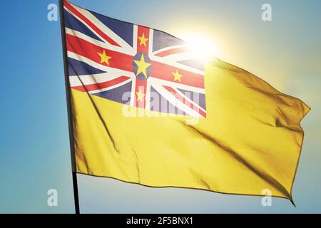 Niue-Flagge winkt vor der Sonne auf dem Wind Stockfoto