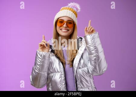 Freudig energetisiert unterhalten nette blonde Frau mit Spaß genießen Sie Urlaub Verschneite Bergtour trägt Sonnenbrille Silber Jacke Winter Hut tanzen Stockfoto