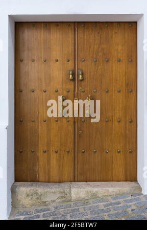 Rustikale Holztür mit goldenen Griffen und Klopfern eines Hauses in Vejer de la Frontera. Cadiz, Spanien Stockfoto