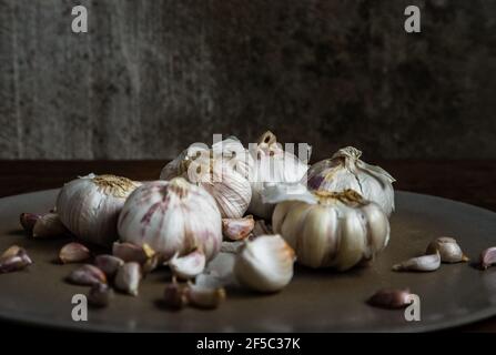 Knoblauchzwiebeln und Knoblauchzehen in Keramikplatte auf Holz rustikalen Tisch. Kopieren Raum Konzept der gesunden Ernährung. Kein Fokus, speziell. Stockfoto