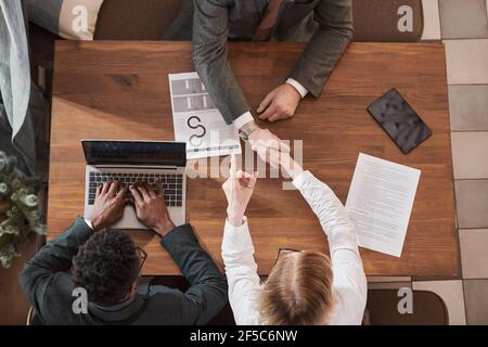 Blick auf das Geschäftsteam, das am Tisch sitzt Bei Geschäftstreffen und Händeschütteln mit Zustimmung Stockfoto