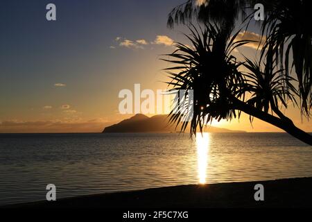 Sonnenaufgang über der Emao Insel in Vanuatu mit Bäumen am Strand im Vordergrund. Stockfoto