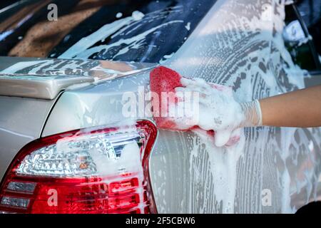 Nahaufnahme Hand tragen Handschuhe halten Schwamm über dem Auto zum Waschen, Car Wash Service-Konzept. Stockfoto