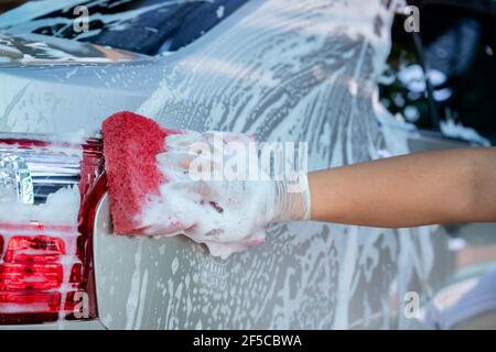 Hand tragen Handschuhe halten Schwamm über dem Auto zum Waschen, Car Wash Service-Konzept. Stockfoto