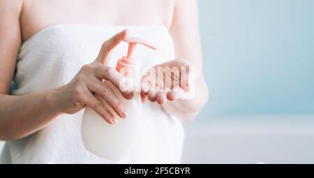 Weibliche Hände Pumpen aus Creme, Lotion, Flüssigseife aus einer weißen Flasche, selektive Fokus. Konzept der Hautpflege. Hygiene einer erwachsenen Frau Stockfoto