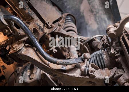 Prüft Stoßdämpfer, Federn und Stabilisatoren mit einer Taschenlampe. Auto  auf einem Reparaturständer. Technische Servicestation für Auto  Stockfotografie - Alamy