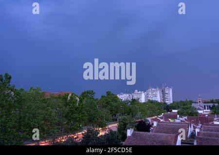 Skyline City at Dusk. Blick auf helle Wege auf der Stadtstraße in hohem Winkel gegen hohe Wohngebäude und bewölkten Himmel. Stockfoto