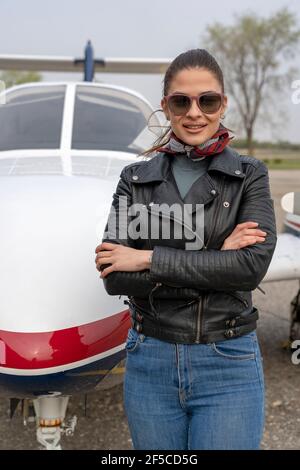 Portrait der schönen jungen Frau Pilot Vorbereitung auf einen Flug. Pilotin in Sonnenbrillen mit modernen Kleinflugzeugen im Hintergrund. Stockfoto