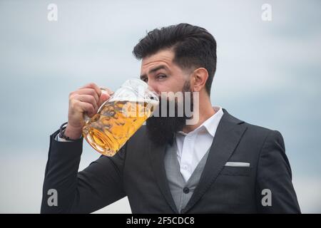 Profilportrait des bärtigen eleganten Mannes, der Bier trinkt. Glücklicher Brauer hält Glas mit Bier. Stockfoto