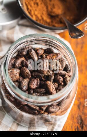 Geröstete Kakaobohnen im Glas auf Holztisch. Stockfoto