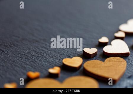 Kleine helle Holzherzen auf dunklem Hintergrund. Valentinstag. Liebeskonzept. Für Text platzieren. Nahaufnahme Stockfoto