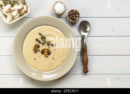 Teller mit köstlicher Pilzsahnesuppe mit Thymian auf dem Holztisch. Horizontale Draufsicht von oben Stockfoto