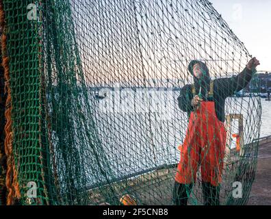 Crosshaven, Cork, Irland. März 2021, 26th. Fischer Jacko Murphy überprüft und flickt die Netze des Trawlers Buddy M im Morgengrauen auf dem Pier in Crosshaven, Co. Cork, Irland. - Kredit; Kredit: David Creedon/Alamy Live Nachrichten Stockfoto