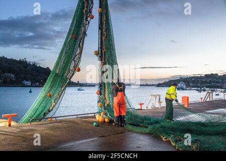 Crosshaven, Cork, Irland. März 2021, 26th. Crew-Mitglieder des Trawlers Buddy M, Jacko Murphy und Roger Murphy überprüfen und flicken die Netze der Boote im Morgengrauen am Crosshaven Pier, Co. Cork, Irland. Kredit; Kredit: David Creedon/Alamy Live Nachrichten Stockfoto