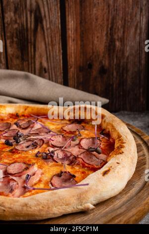 Italienische Pizza mit Fleisch, Käse und Basilikum aus nächster Nähe. Stockfoto