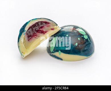 Bonbons aus gehärteter Schokolade mit glänzendem lackiertem Körper und Fruchtfüllung mit unscharfen Elementen. Stock-Fotografie. Stockfoto