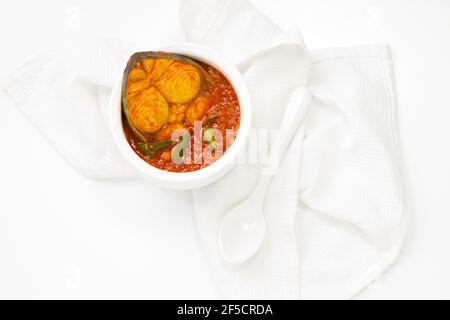 Seer Fish Curry, traditionelles indisches Fischcurry, kerala Special, in einer weißen Schüssel mit Curryblättern und frischem grünen Chili auf einem weißen garniert angeordnet Stockfoto