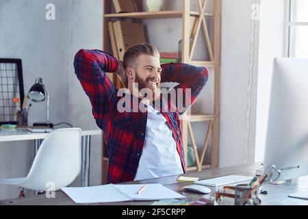Glücklicher junger Mann mit Pause in seinem Büro Stockfoto