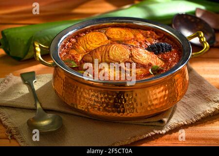 Seer Fish Curry, traditionelles indisches Fischcurry, kerala Special, arrangiert in einer Kupferschüssel garniert mit malabar Tamarinde und frischem grünem Chil Stockfoto