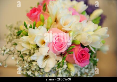 Üppiges Bouquet aus bunten Rosen gepaart mit weißen Freesias und Frühlingsgartenblumen, frisches Blumenarrangement als perfektes natürliches Accessoire geschaffen Stockfoto