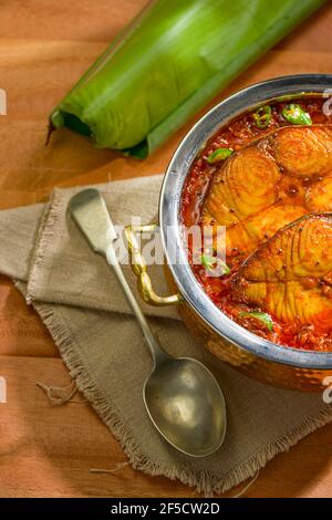 Seer Fish Curry, traditionelles indisches Fischcurry, kerala Special, arrangiert in einer Kupferschüssel garniert mit malabar Tamarinde und frischem grünem Chil Stockfoto