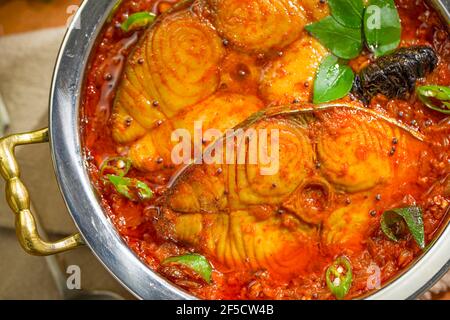 Seer Fish Curry, traditionelles indisches Fischcurry, kerala Special, arrangiert in einer Kupferschüssel garniert mit malabar Tamarinde und frischem grünem Chil Stockfoto