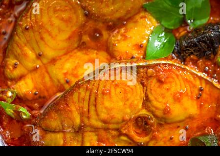 Seer Fish Curry, traditionelles indisches Fischcurry, kerala Special, arrangiert in einer Kupferschüssel garniert mit malabar Tamarinde und frischem grünem Chil Stockfoto