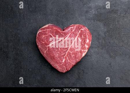 Herzförmig rohes, frisches Rindersteak auf Metallhintergrund Stockfoto