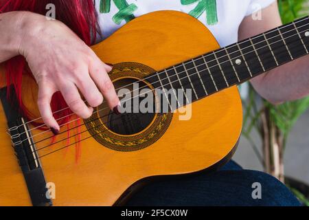 Crop weiblich in T-Shirt mit Transgender Symbol berühren Saiten Der akustischen Gitarre während des Liedes Stockfoto