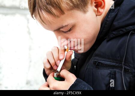 Das Kind raucht eine Zigarette aus der Nähe der Straße Stockfoto