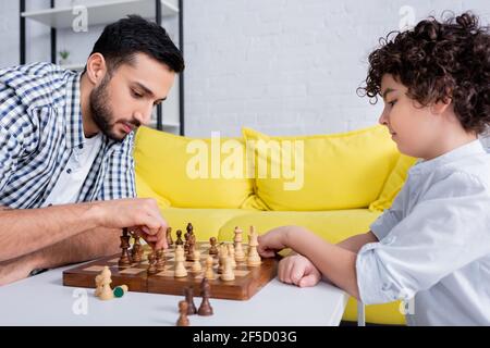 Arabischer Mann spielt Schach mit Sohn zu Hause Stockfoto