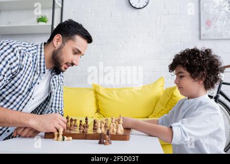 Seitenansicht von arabischem Vater und Sohn, die Schach spielen Zu Hause Stockfoto