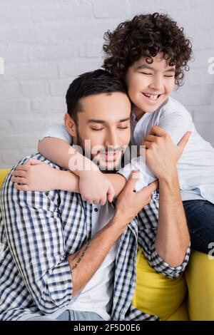 Happy muslim Vater und Sohn umarmen, während mit Spaß an Zu Hause Stockfoto