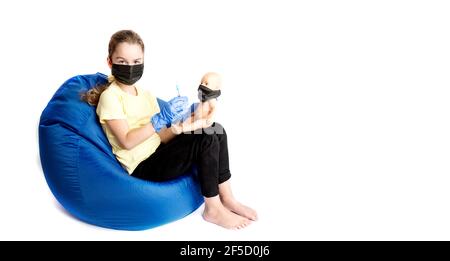 Das Mädchen spielt einen Arzt mit einer Puppe. Die Realität des Coronavirus im Leben von Kindern. Einspritzung gegen covid19. Stockfoto