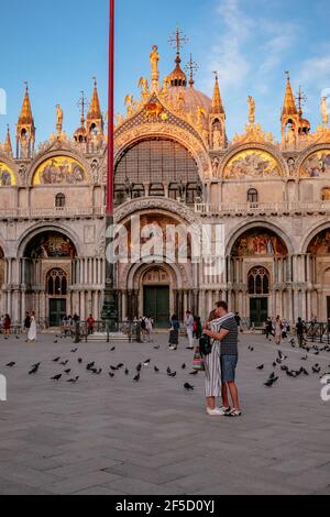 Ein Paar umarmt vor der Markusbasilika in Venedig bei Sonnenuntergang - die romantischste Stadt der Welt, Italien Stockfoto