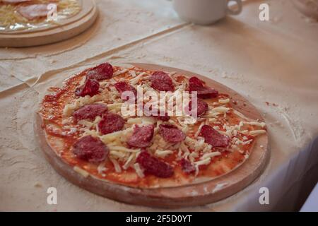 Eine Reihe Pizza auf einem hölzernen Schneidebrett bestreut mit Mehl Stockfoto