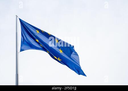 Die Flagge der Europäischen Union winkt von einem Fahnenmast. Vor dem blauen Hintergrund bilden die goldenen Sterne einen Kreis als Symbol der Einheit und Solidarität. Stockfoto