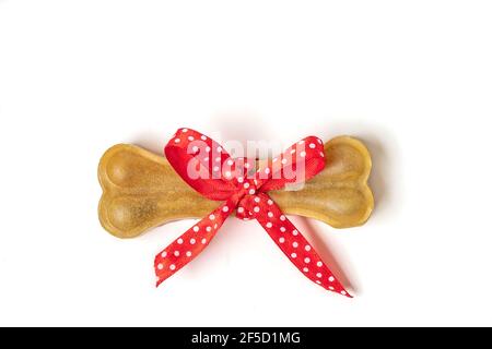 Knochen für Hunde mit rotem Bogen isoliert auf weißem Hintergrund Draufsicht Flat Lay Delicious Leckerbissen für Ihr geliebtes Haustier Food for Animals Konzept Stockfoto