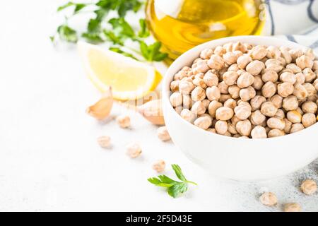 Kichererbsen in weißer Schüssel am hellen Küchentisch. Stockfoto