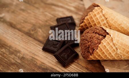 Schokoladeneis in Waffelkegel auf Bastelpapier Auf einem hölzernen Hintergrund Stockfoto