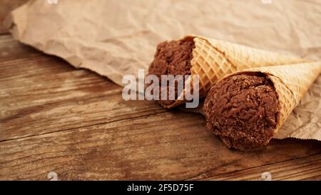 Schokoladeneis in Waffelkegel auf Bastelpapier Auf einem hölzernen Hintergrund Stockfoto