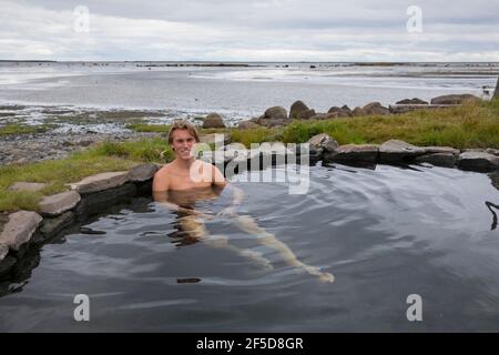 Mann Baden im Krosslaug natürlichen Geothermie-Pool direkt an der Küste, Island, Birkimelur Stockfoto