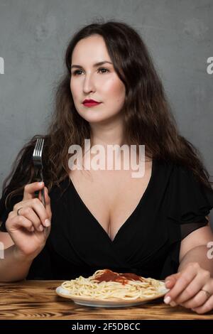 Eine schöne junge Frau isst italienische Spaghetti Pasta. Das Brünette Mädchen haben Mittagessen in einem Café Stockfoto