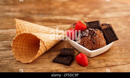 Schokoladeneis in einer Schüssel. Dessert mit Schokolade und Erdbeeren dekoriert Stockfoto