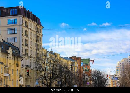 Kiew, Ukraine, März 2020. Straße mit schönen bunten Häusern im klassischen Stil gegen den blauen Himmel an einem sonnigen Tag. Eine Straße, die sich in die erstreckt Stockfoto