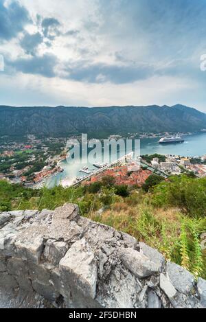 Ein Kreuzfahrtschiff wartet, ankert auf der Bucht, von der Festung Kotor gesehen, und die Sonne beginnt, über den Hügeln auf der anderen Seite der Bucht von Kotor in spät untergehen Stockfoto