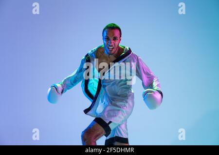 High-Fashion gestylte Mann in weißem Outfit Schnupfbox isoliert über Verlaufshintergrund in Neonlicht Stockfoto