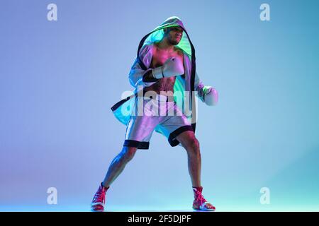 High-Fashion gestylte Mann in weißem Outfit Schnupfbox isoliert über Verlaufshintergrund in Neonlicht Stockfoto