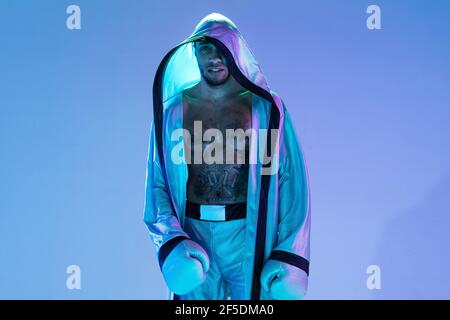 High-Fashion gestylte Mann in weißem Outfit Schnupfbox isoliert über Verlaufshintergrund in Neonlicht Stockfoto