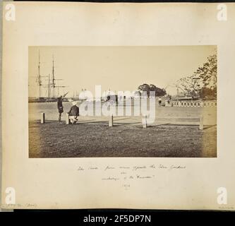 Kalkutta; 'The Strand' in der Nähe der Eden Gardens. Blick auf eine Kreuzung von Strand Road und Gostha Paul Sarani auf dem Eden Gardens Cricket Grounds entlang des Hooghly River. Auf der linken Seite sind angedockte Schiffe entlang des Flusses zu sehen, und in der Mitte der Kreuzung steht eine Pferdekutsche. Ein Mann sitzt auf einem Geländer im Vordergrund neben einem Mann, der neben ihm steht. Eine Steinwand mit einem perforierten Kreismuster verziert läuft um die Ecke auf der anderen Seite der Straße mit einem Mann sitzt darauf.. (Recto, Bild) unten rechts, im Negativ handgeschrieben: '1727' (Recto, Mount) unten links, ha Stockfoto